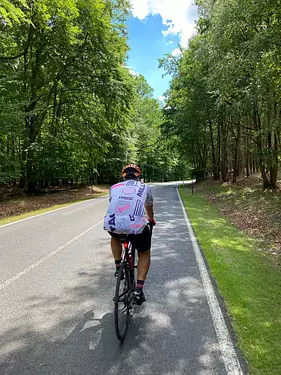 a person riding a bicycle on a road surrounded by trees
