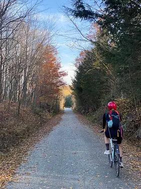 Kerianne riding her bicycle on a path surrounded by trees