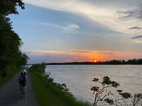 a person riding a bicycle on a path by a body of water