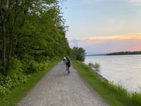 a group of people riding bikes on a path by a body of water