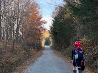 Kerianne riding her bicycle on a path surrounded by trees