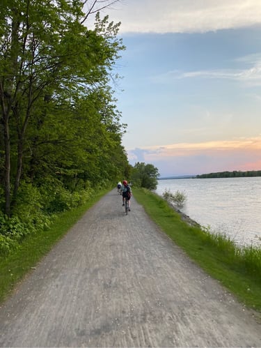 a group of people riding bikes on a path by a body of water