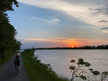 a person riding a bicycle on a path by a body of water