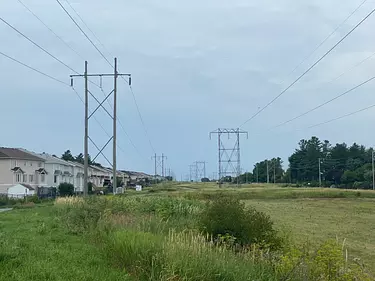 power lines and grass with houses and trees in the background