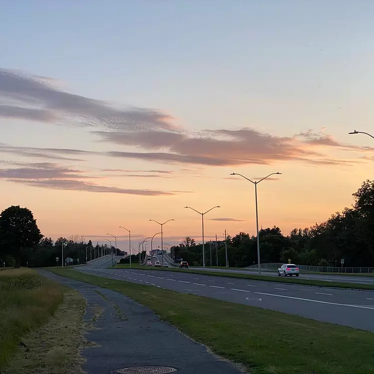 a road with cars on it and a sunset in the background