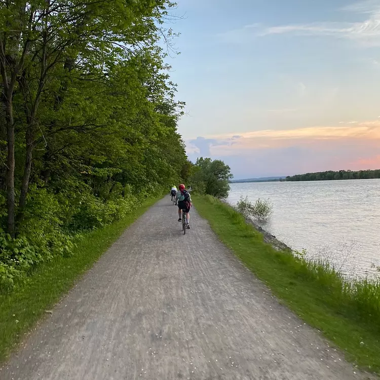 a group of people riding bikes on a path by a body of water