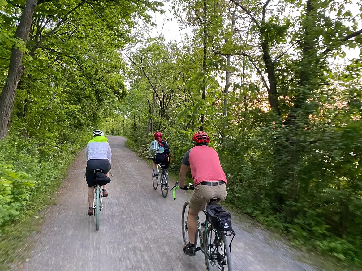 a group of people riding bikes on a path in the woods