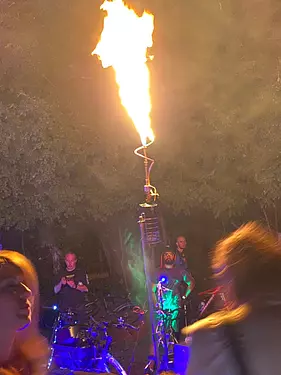 a group of people on a stage with a fire in the air