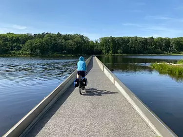 a person riding a bicycle on a road next to a body of water