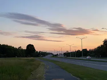 a road with cars on it and a sunset in the background