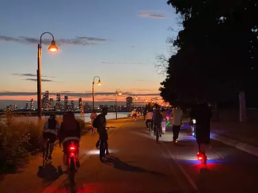 a group of people riding bikes on a street at night